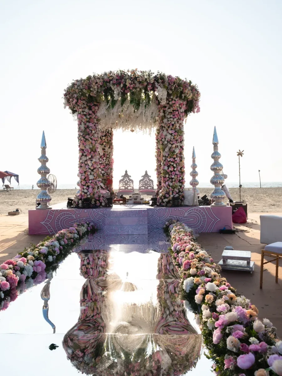 Beach wedding mandap with a mirrored floral aisle in Goa
