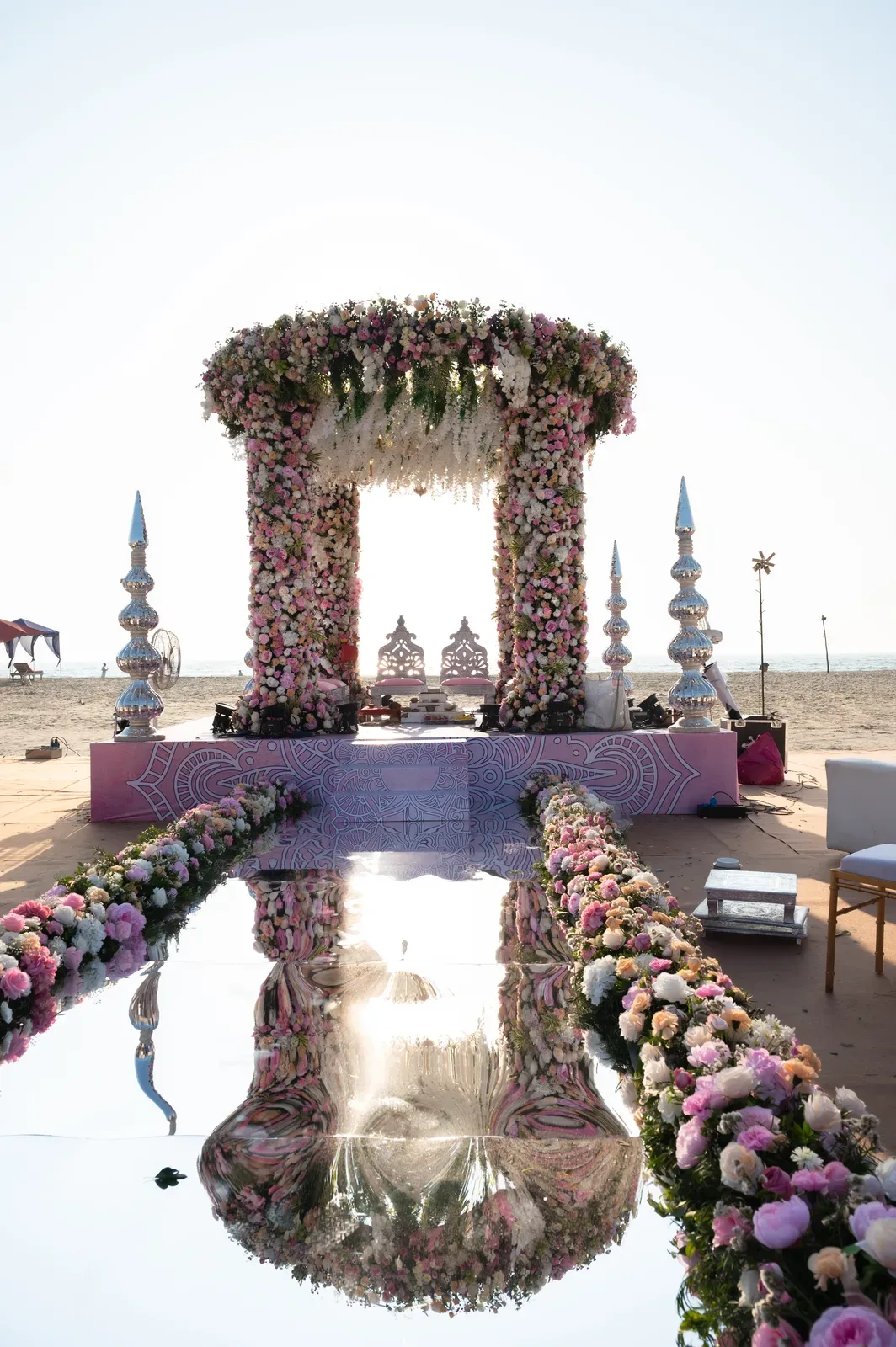 Beach wedding mandap with a mirrored floral aisle in Goa