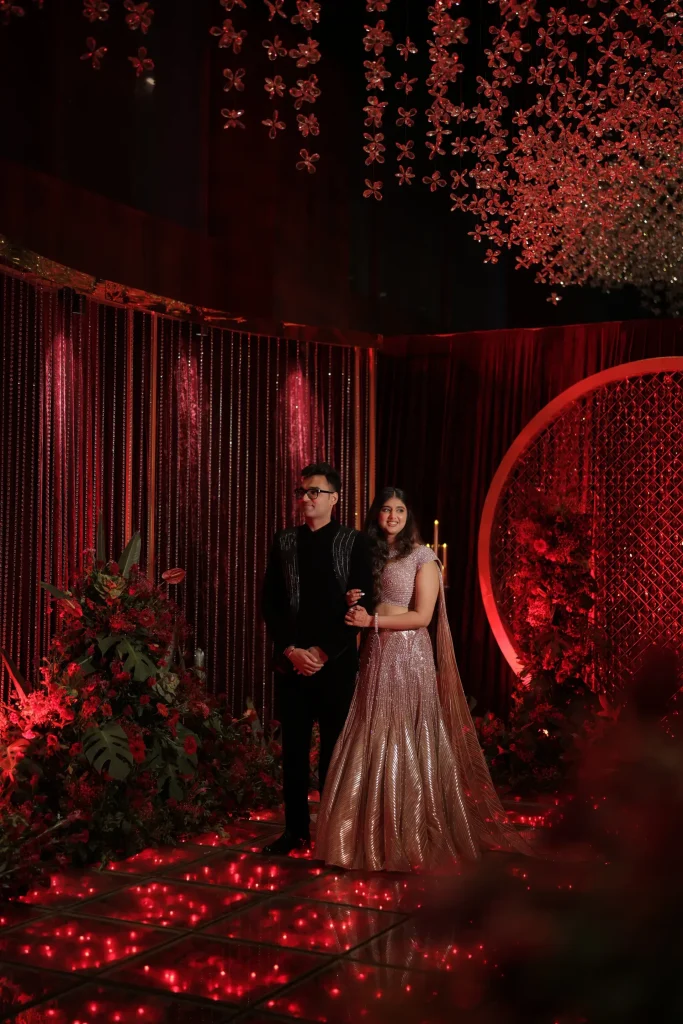 Couple at a ceremony with a red floral backdrop