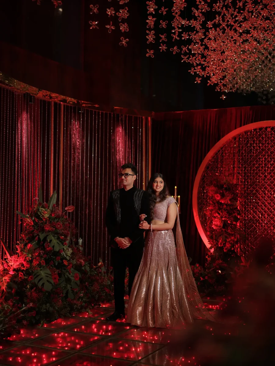 Couple at a ceremony with a red floral backdrop